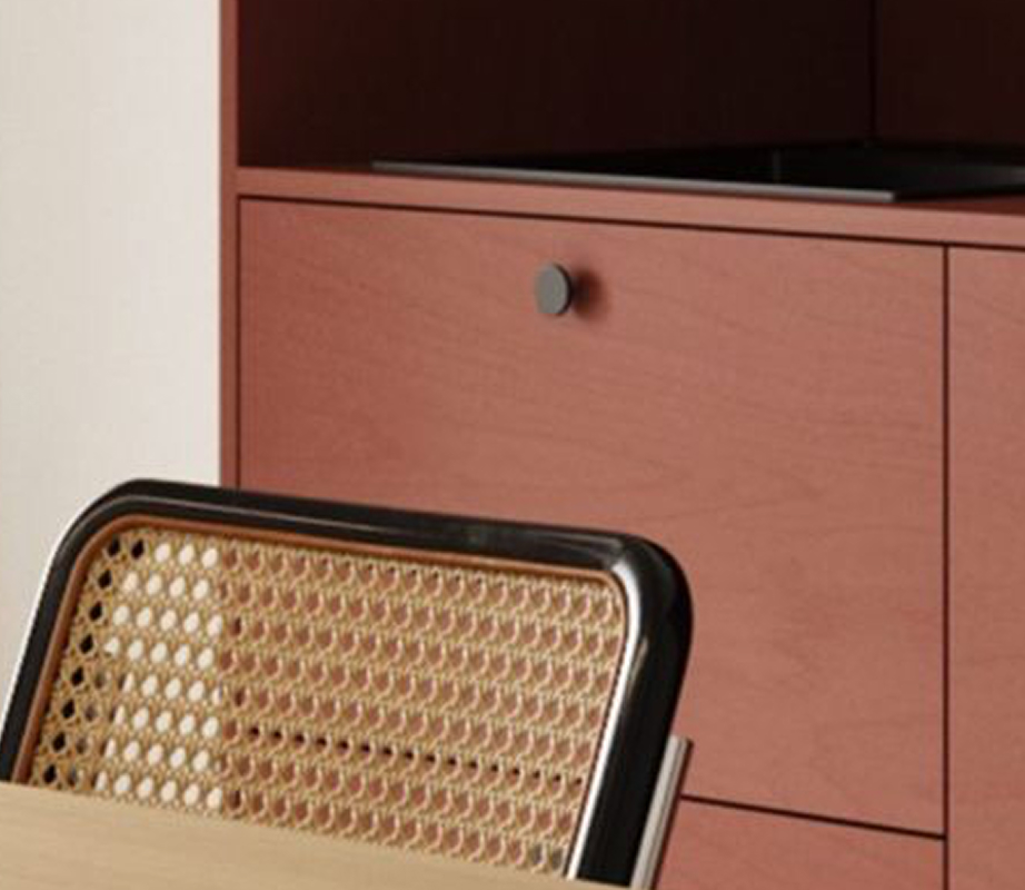 Close-up of a rattan chair in front of a terracotta sideboard with a TV in a vacation rental