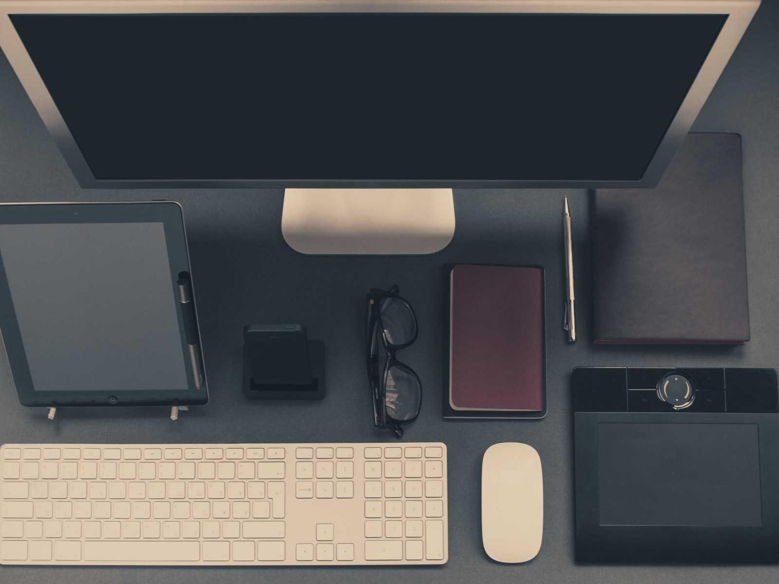 Aufger&auml;umter Schreibtisch mit Monitor, Tablet, Tastatur und Brille von oben